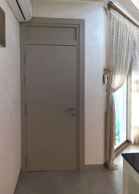 Puerta de entrada de aluminio lisa color gris beige con fijo superior