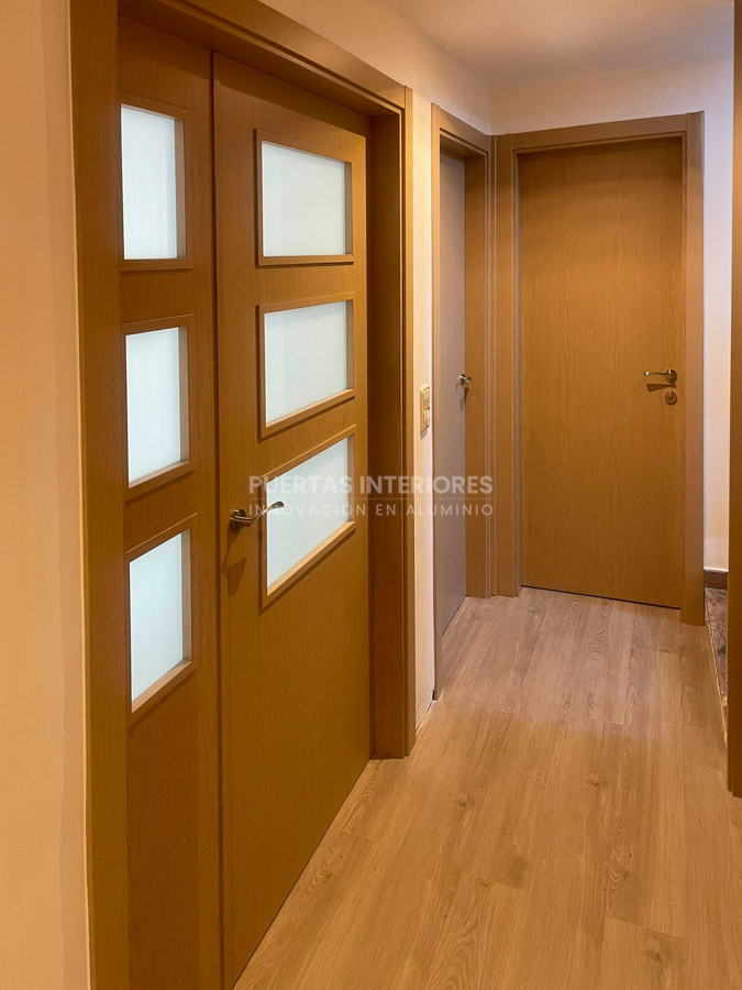 Puertas interiores de aluminio acabado haya instaladas en pasillo
